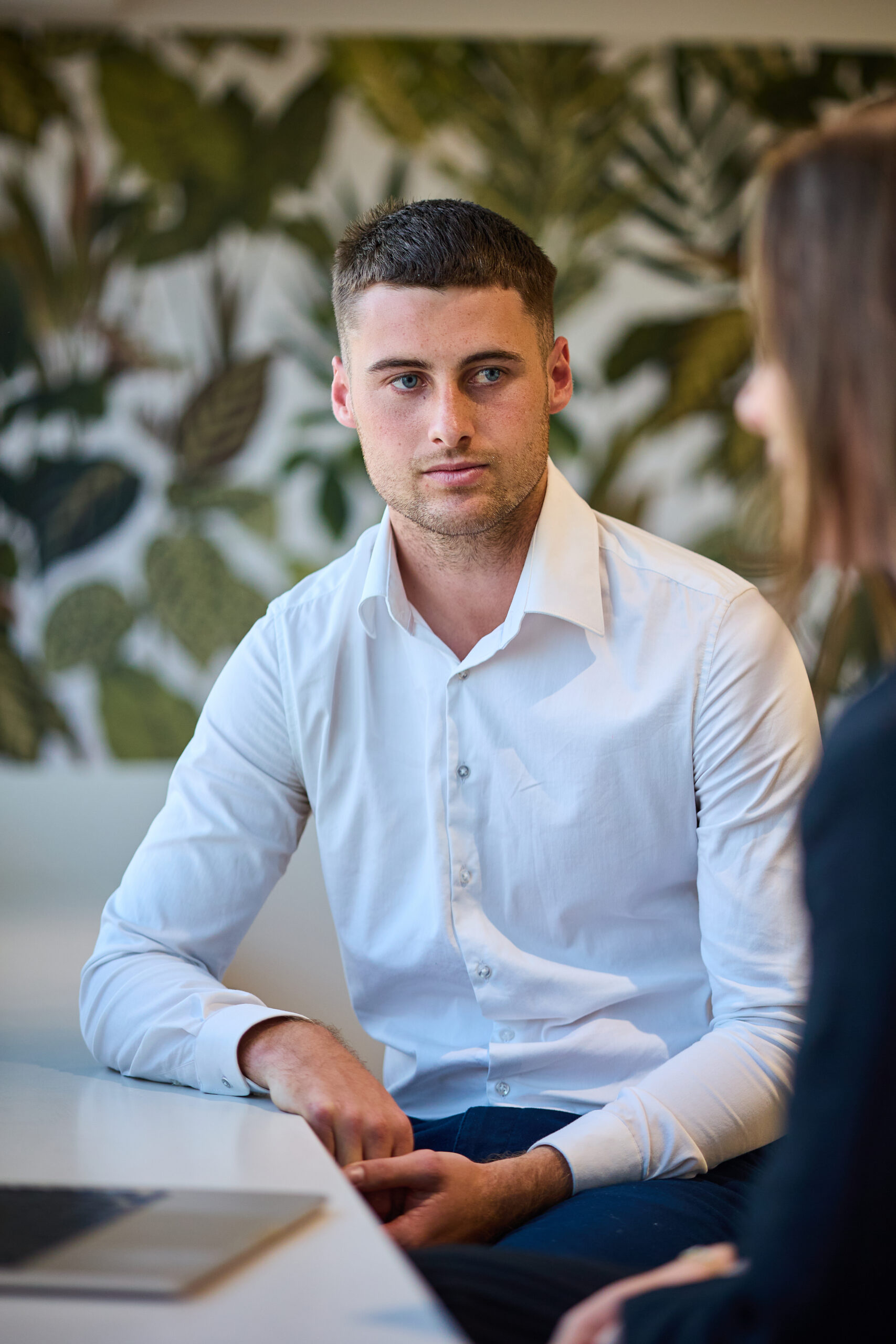 Legal professionals discuss Queensland work injury damages claims at a table with a laptop, set against a leafy wall backdrop.